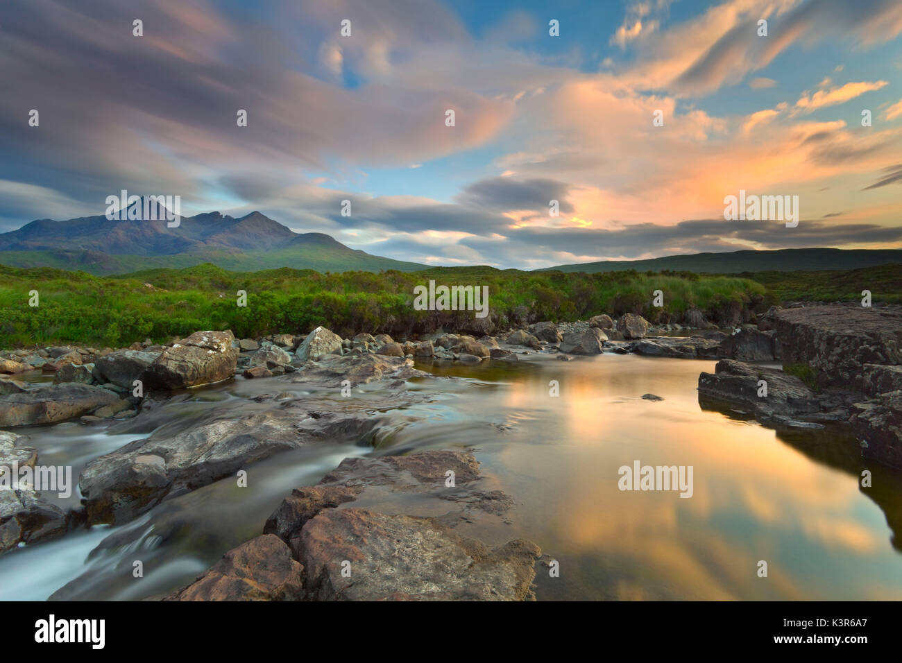 Isola di Skye in Scozia, l'Europa. L'ultimo tramonto colori riflessi nell'acqua. Sullo sfondo le cime del Black Cuillin. Foto Stock