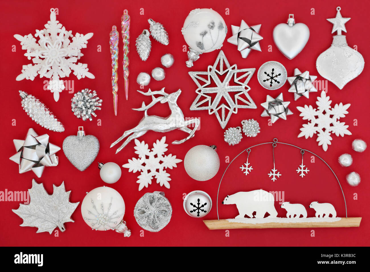Simboli del Natale con la pallina con decorazioni in argento e bianco su sfondo rosso. Foto Stock