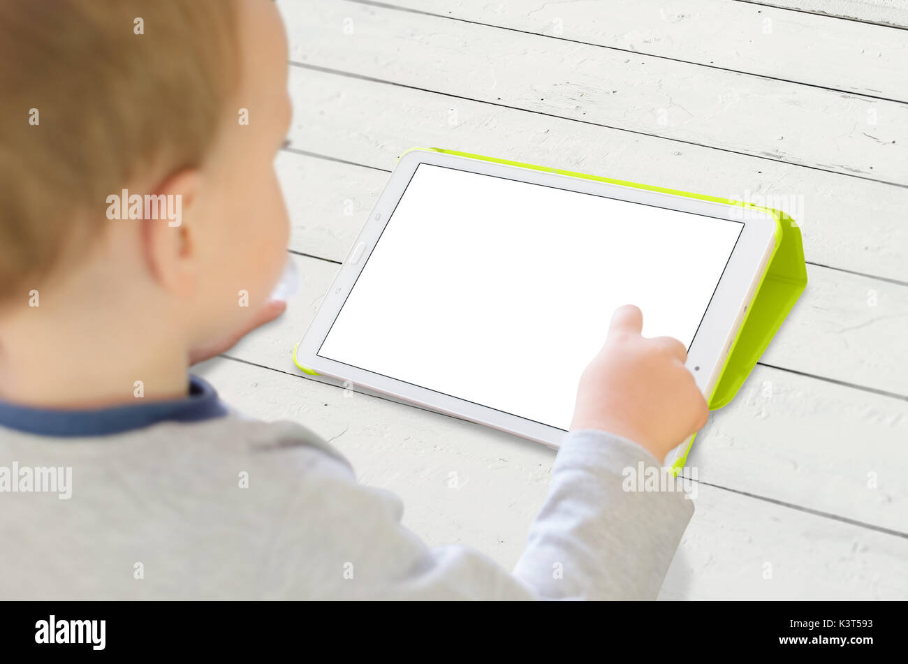 Ragazzo utilizzano tablet su bianco scrivania in legno. Isolato bianco, schermata vuota per app mockup. Foto Stock