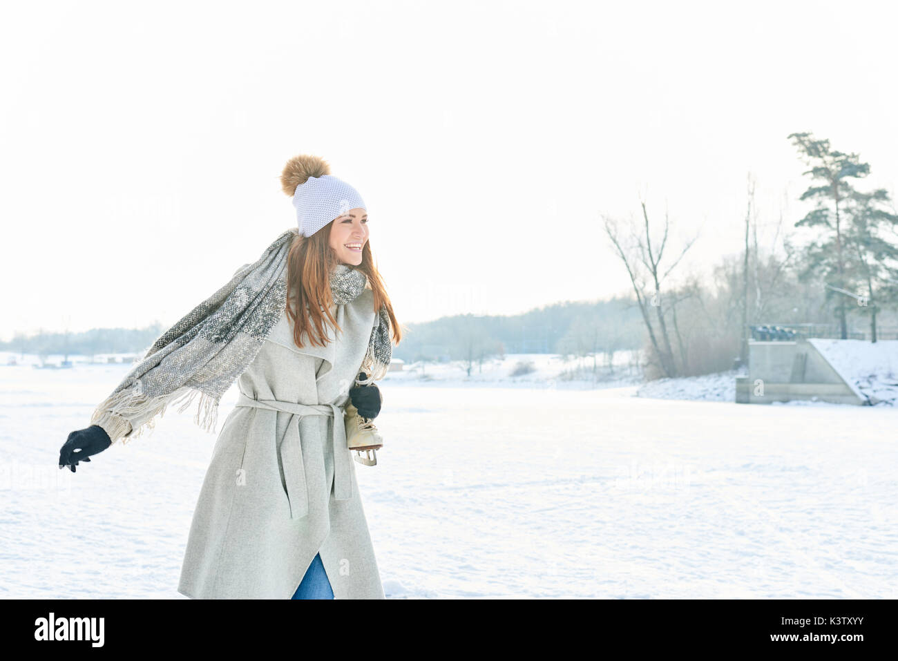 Donna con ice-pattini sorrisi con gioia durante la sua passeggiata invernale Foto Stock