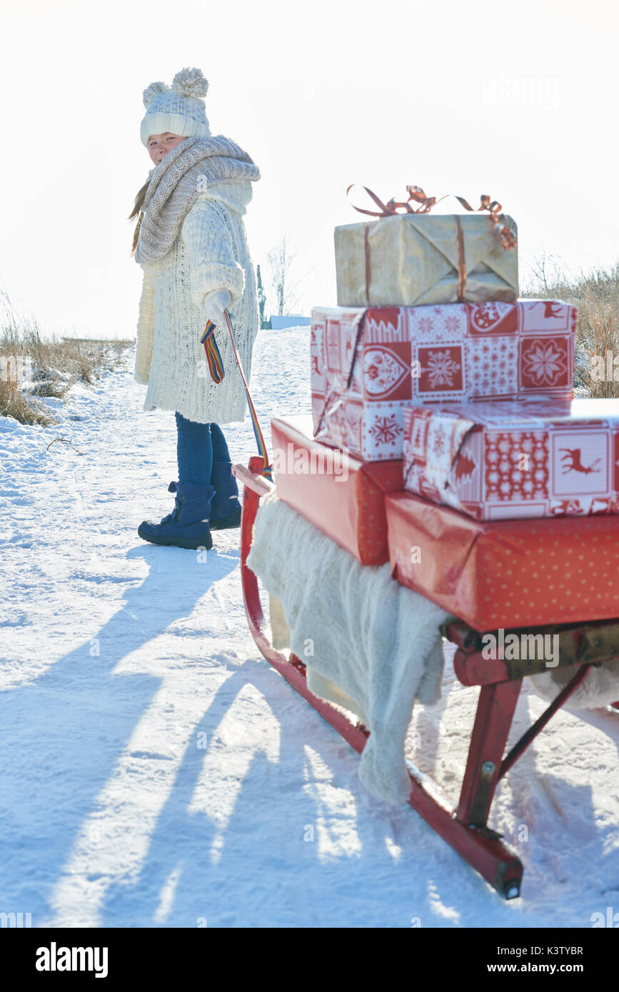 Ragazza tirando la slitta piena di regali di Natale in inverno Foto Stock
