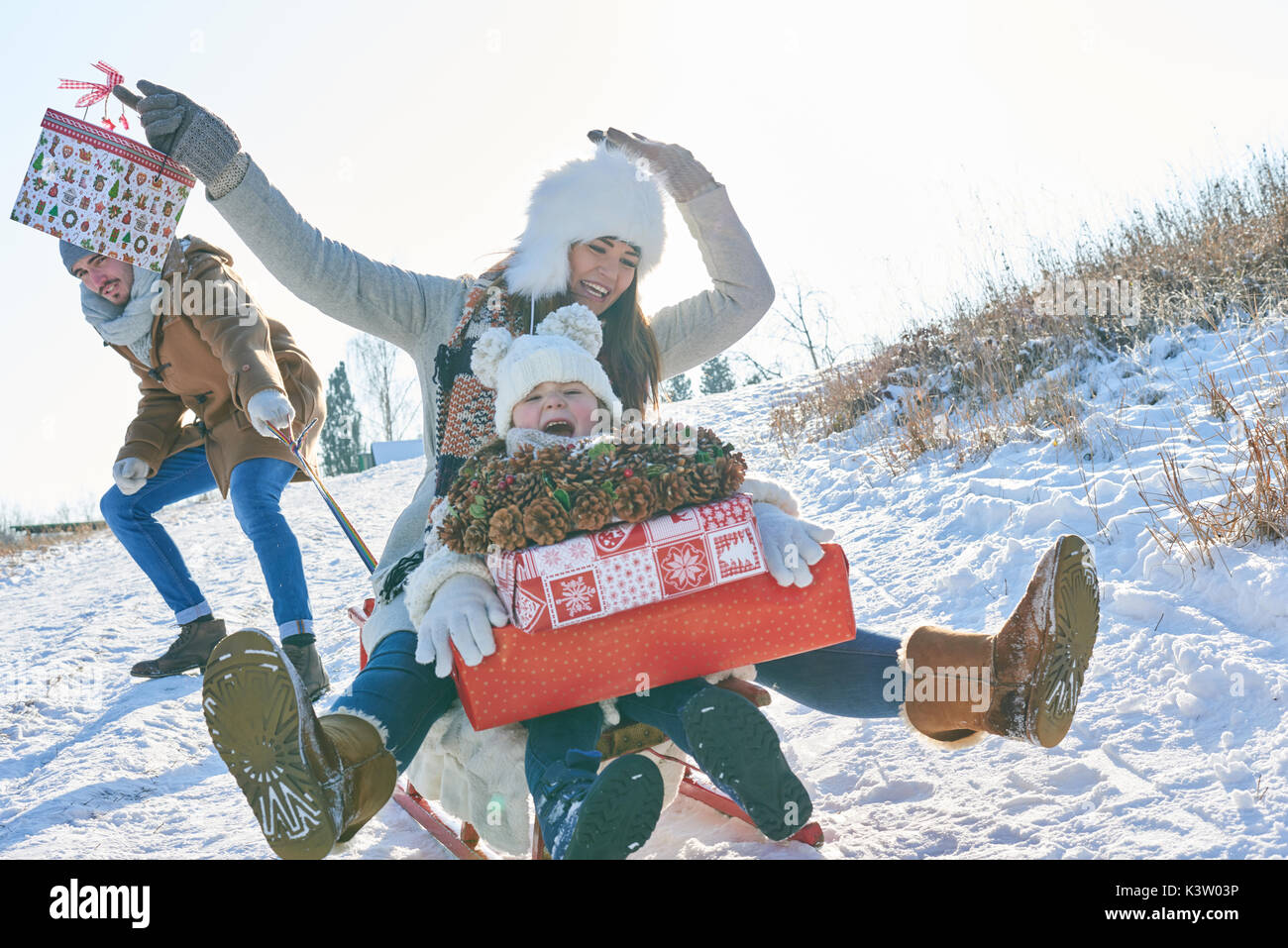 Famiglia slittino in inverno con entusiasmo tenendo i regali di natale Foto Stock