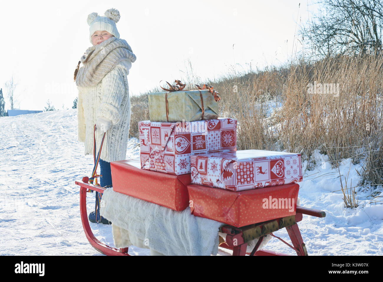 Bambino di trasportare i regali di natale con slitta in inverno Foto Stock