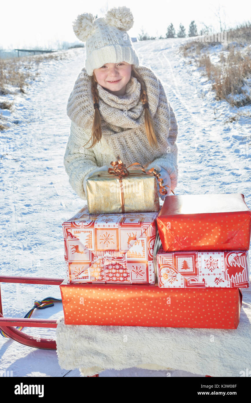 Bambina offre i regali di Natale in inverno con slitta Foto Stock