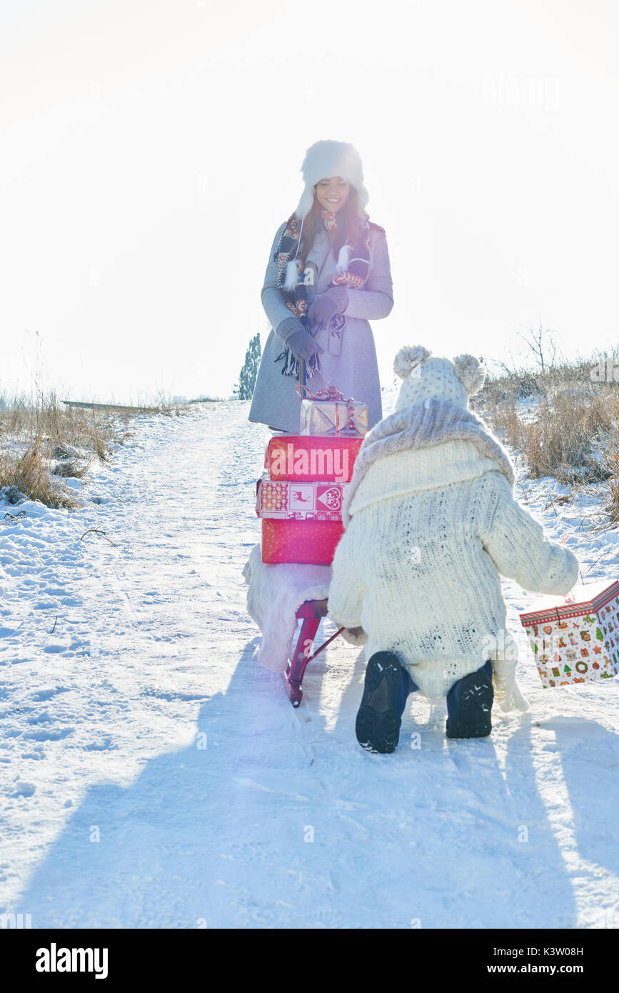 La madre e il bambino consegnare i regali di natale con slitta in inverno Foto Stock