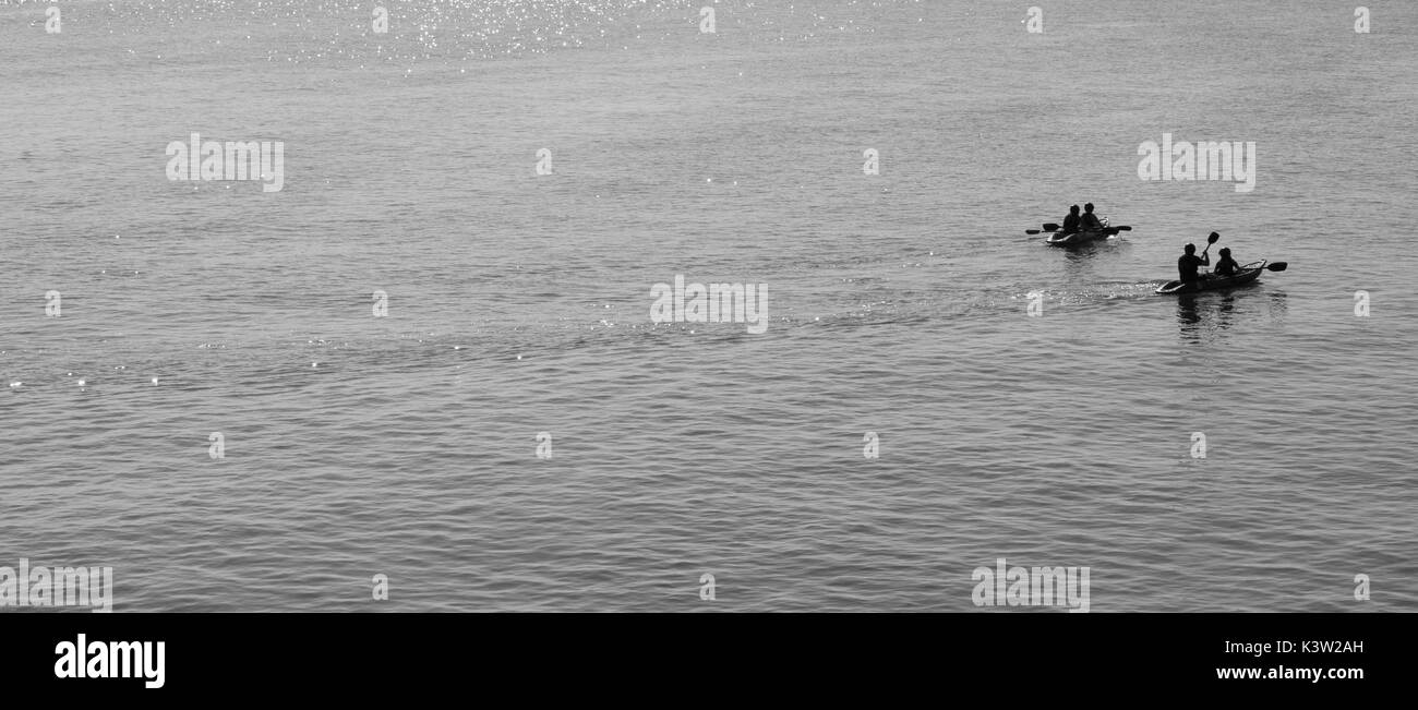 Canoe paddle lentamente fino a riva molto su acqua calma sul lungomare di Hastings. Foto Stock