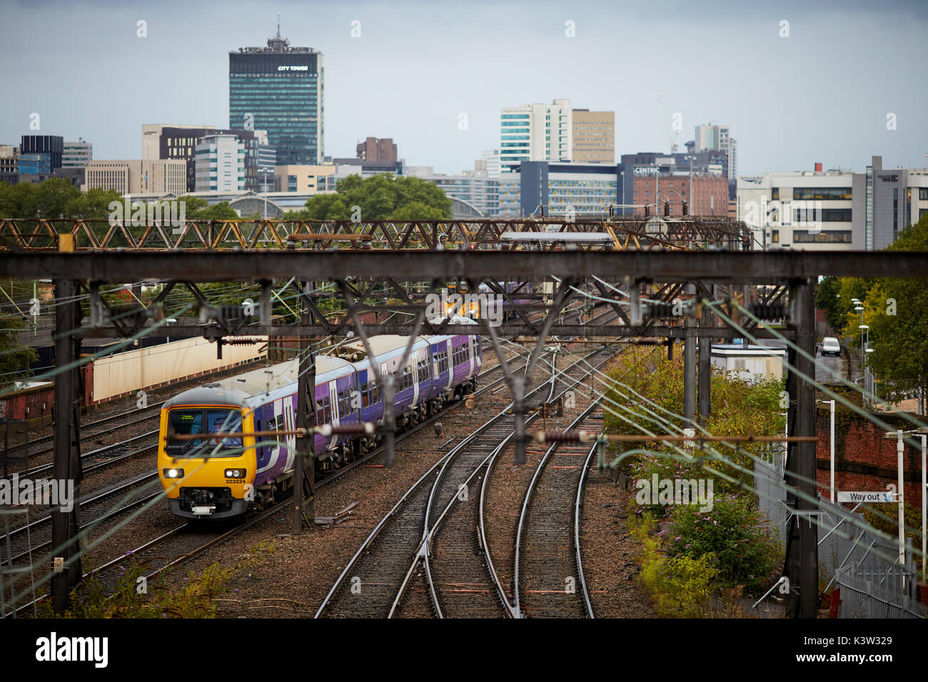 Northern British Rail Class 323 elettrico unità multiple di franchising la linea ferroviaria da Ardwick che conduce alla stazione ferroviaria Manchester Piccadilly Station con city skylin Foto Stock