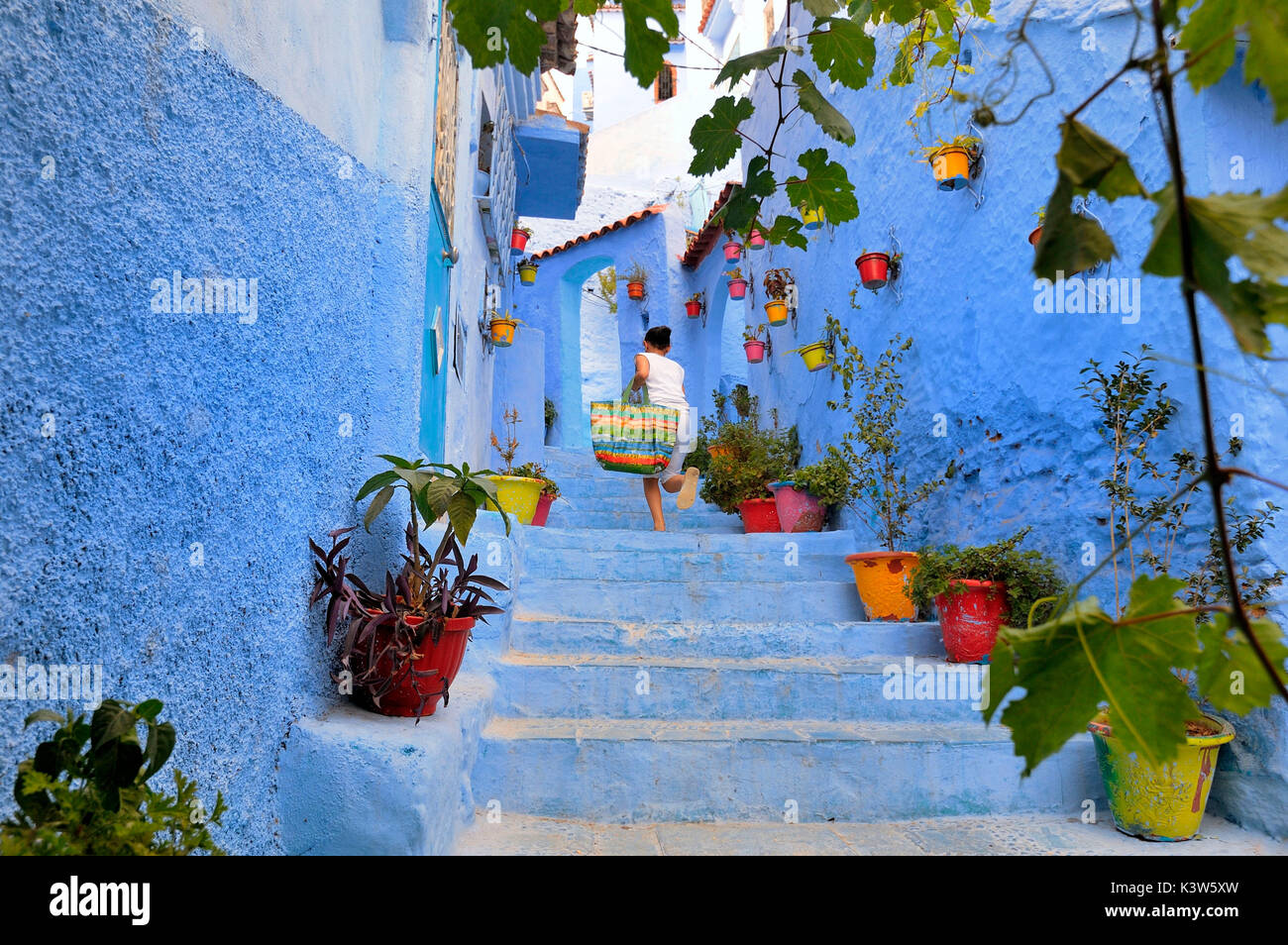 Ragazza correre su per le scale nella medina di Chefchaouen. Tangeri-Tétuan, Marocco, Africa del Nord. Foto Stock