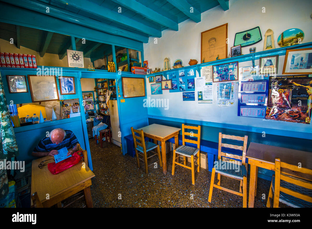 Isola di Amorgos, Cicladi Grecia, l'Europa. L'interno e la vecchia taverna con sedie, tavolo e un vecchio di lettura Foto Stock