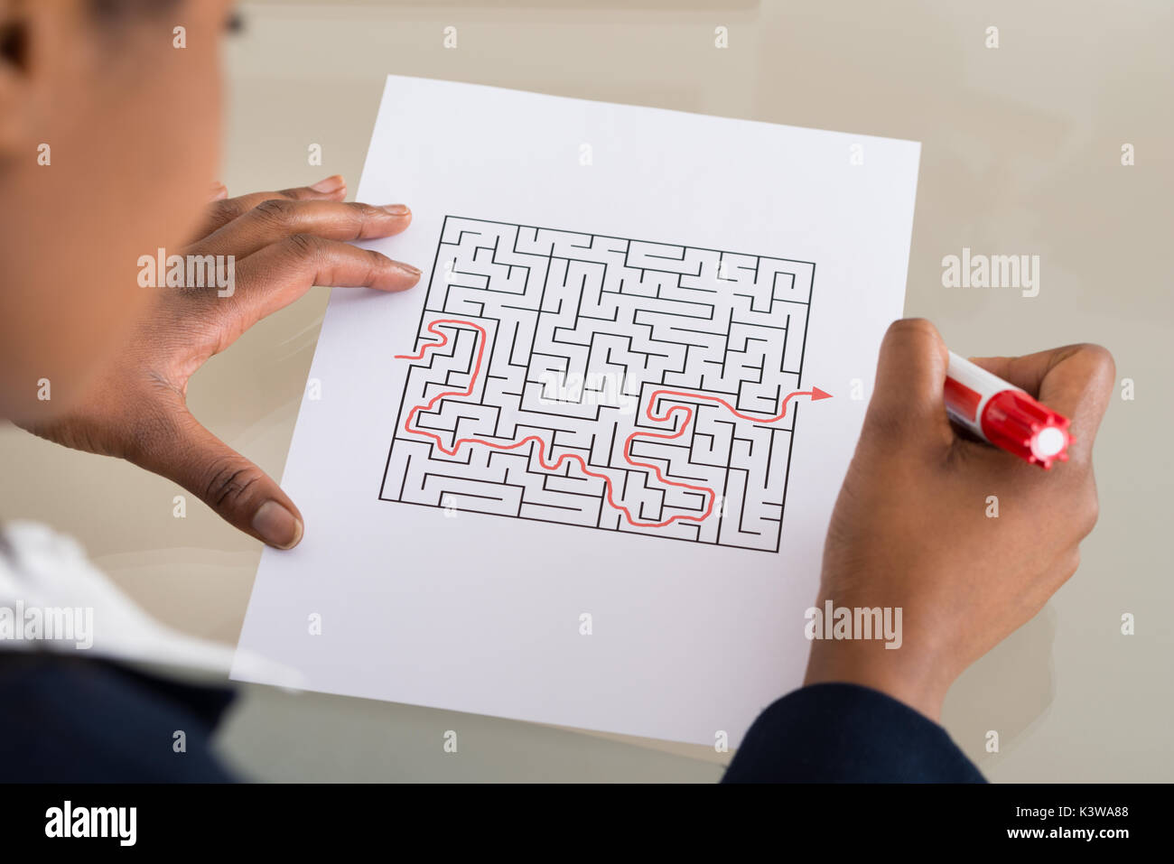 Close-up di una imprenditrice risolvendo puzzle labirinto con indicatore rosso Foto Stock