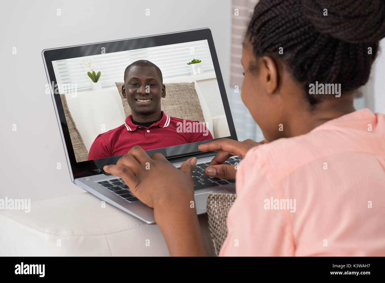 Close-up di giovane donna africana la chat video con Uomo che utilizza un notebook Foto Stock