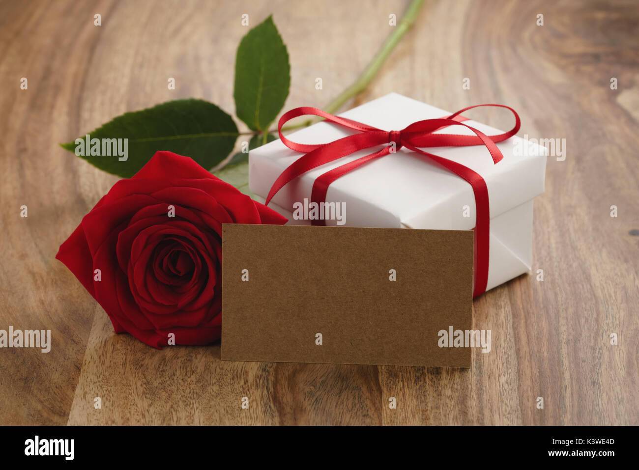 Red Rose con confezione regalo e una scheda su un tavolo di legno Foto Stock