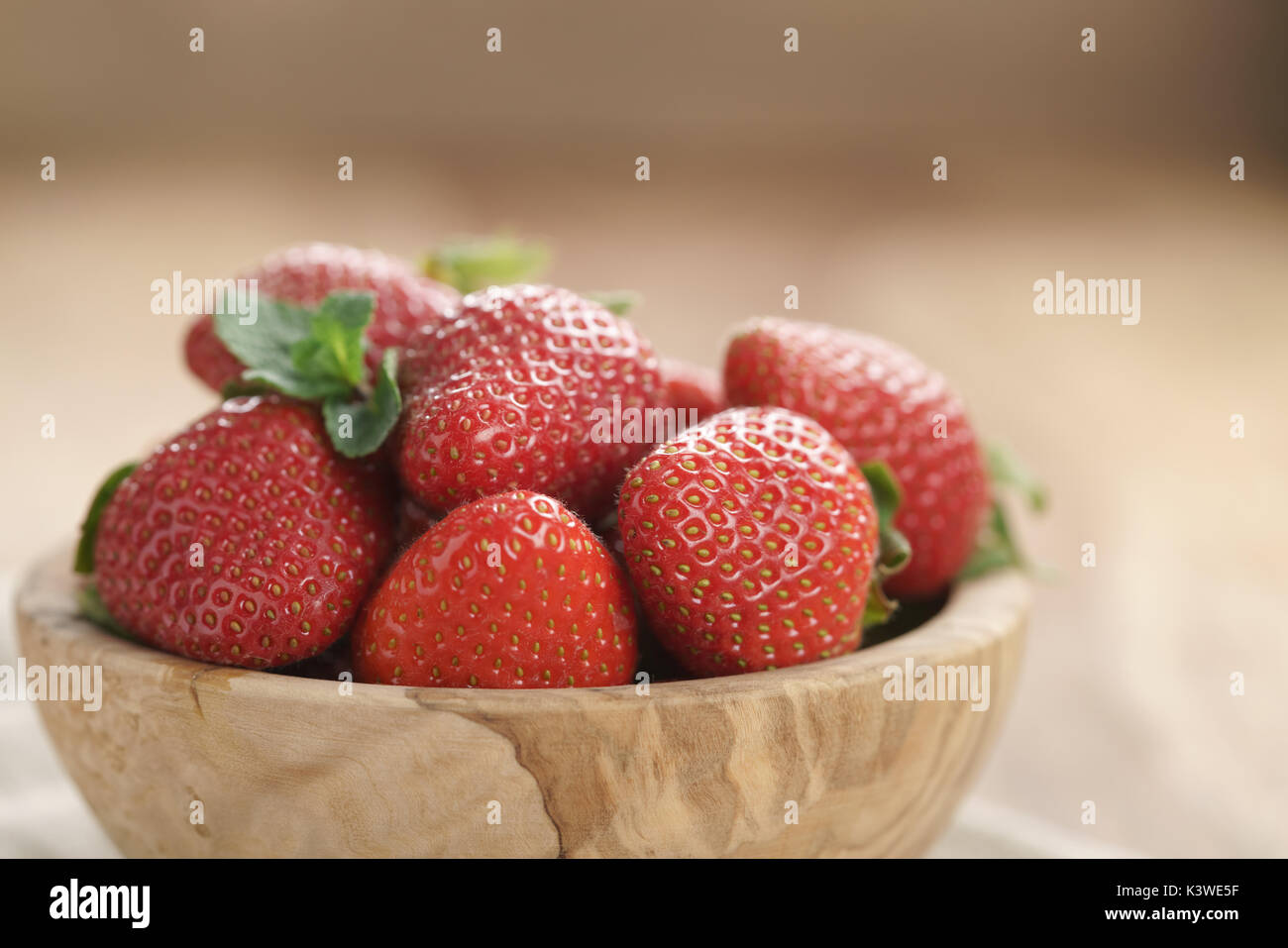 Fragole fresche nella ciotola sul tavolo di legno Foto Stock