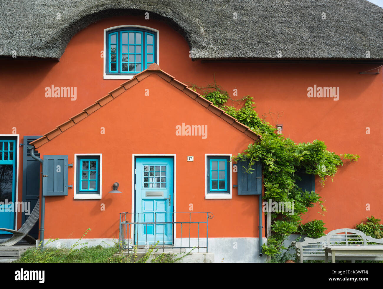 Terrakotta Fassade mit blauen Sprossenfenster und Tür und Reedtach eines Hauses auf dem Graswarder, Heiligenhafen, Schleswig-Holstein, Germania Foto Stock