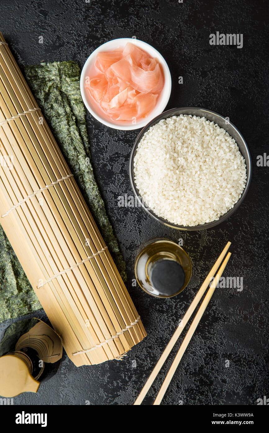 Il sushi ingrediente. Nori, riso, aceto di riso, zenzero sott'aceto e salsa di soia sulla tavola nera. Foto Stock