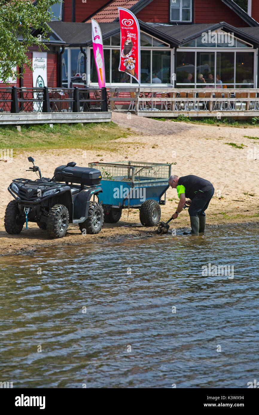 Un uomo che pulisce la spiaggia Foto Stock