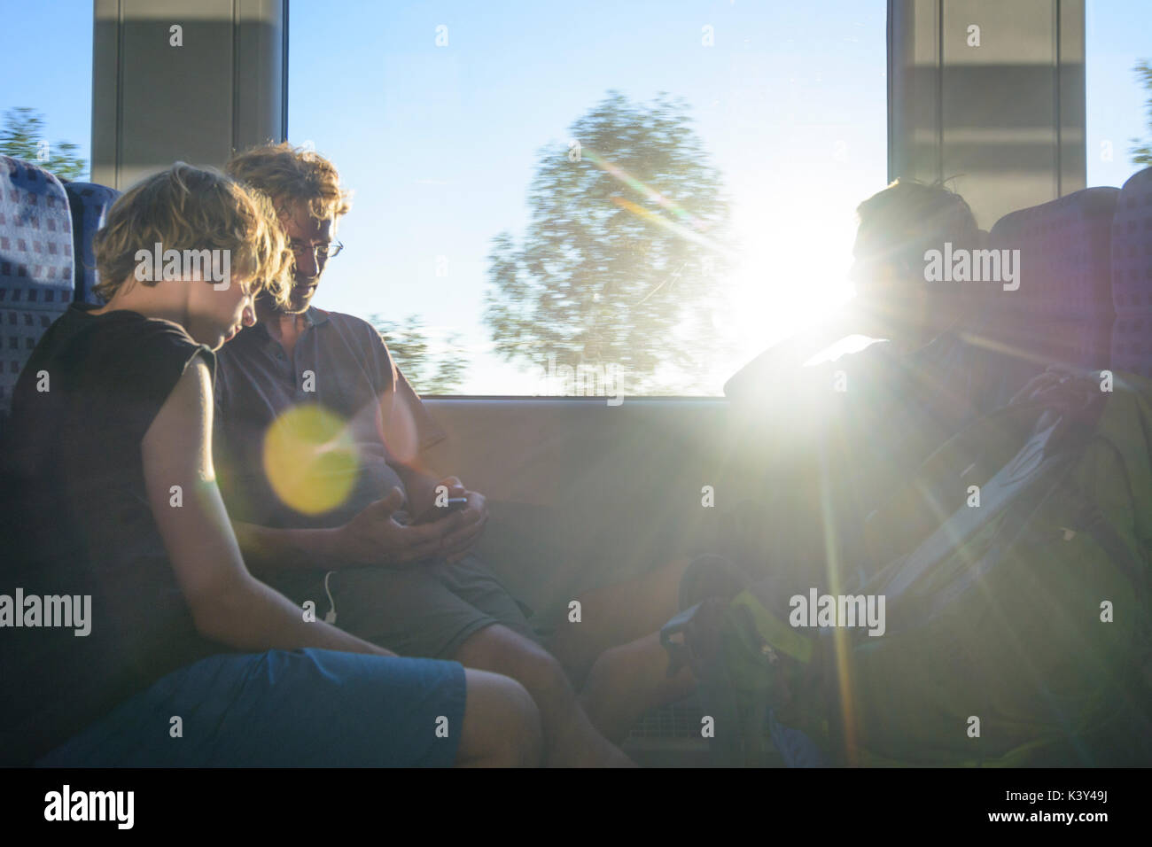 Padre uomo, 2 ragazzi seduti in treno, sun, Augsburg, Schwaben, Svevia, Baviera, Baviera, Germania Foto Stock