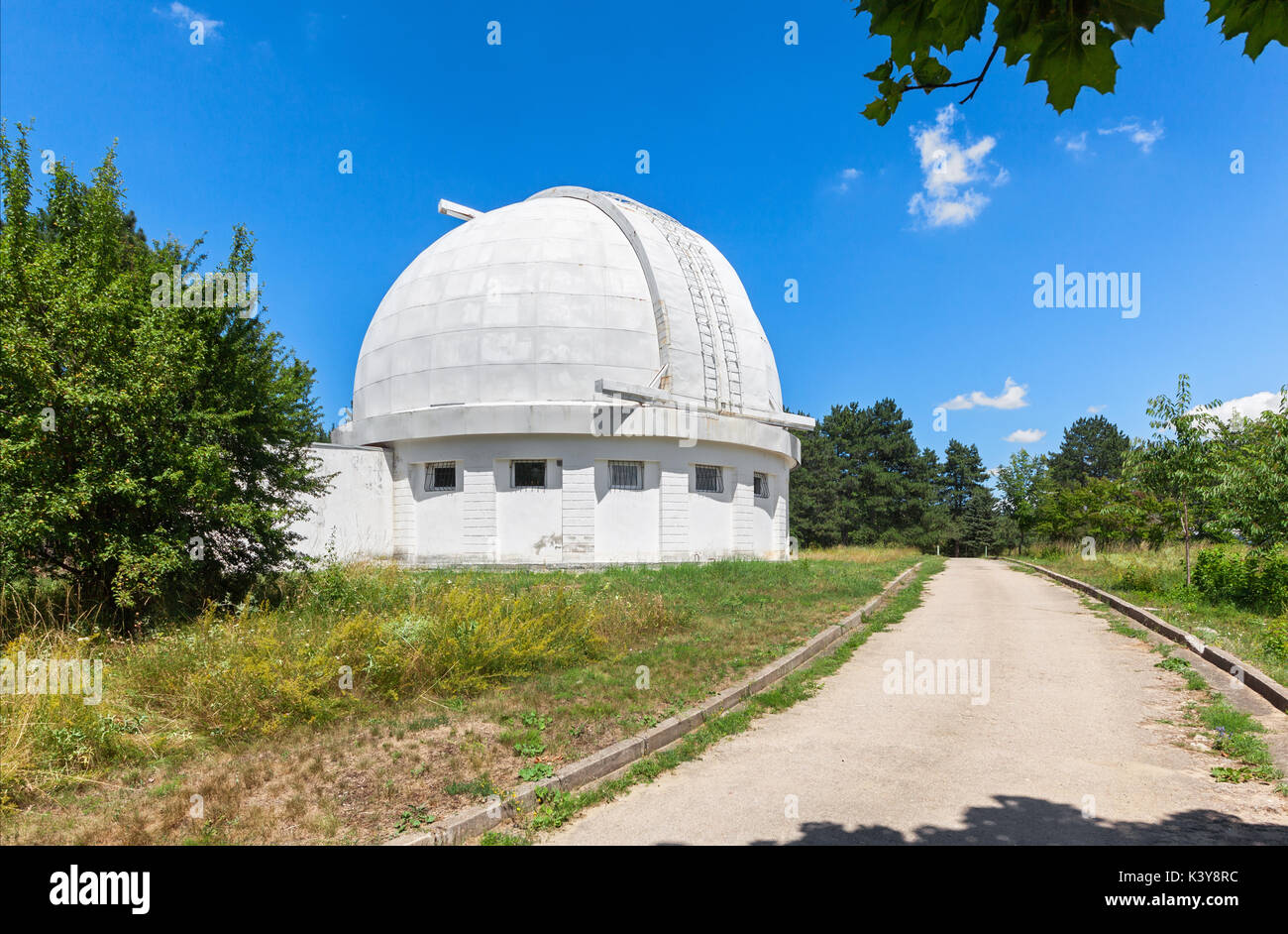 Road accanto all'Osservatorio edificio con una cupola apribile per la coronograph. La cupola del telescopio durante il giorno. Foto Stock