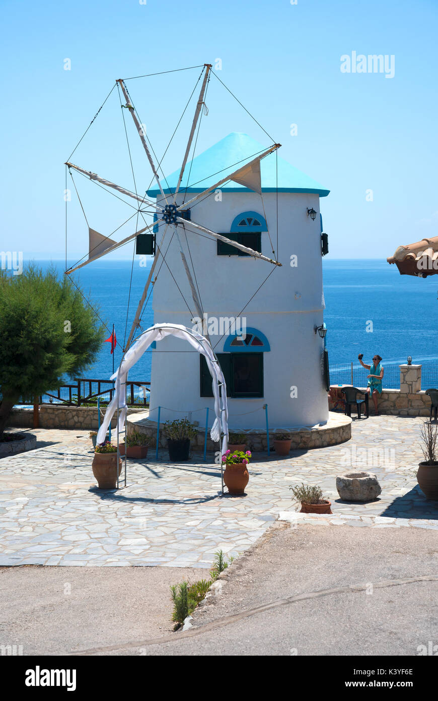 Ragazza tenendo un selfie accanto alla tradizionale mulino a vento greco a capo Skinari, sulla punta nord di Zante Foto Stock