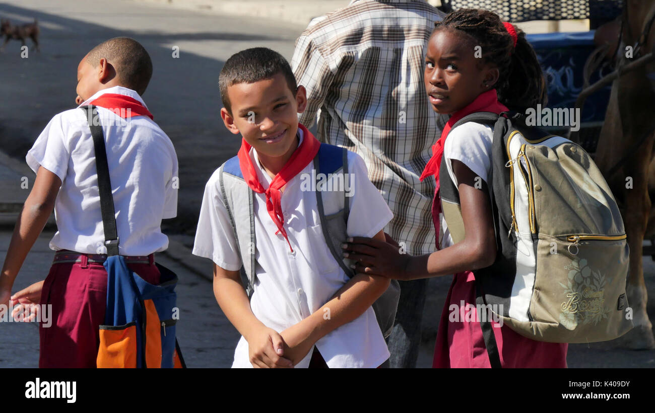 School girl in rosso pionieri sciarpa tirando via il suo ragazzo fiend dal contatto con i turisti americani. Cienfuegos, Cuba Foto Stock