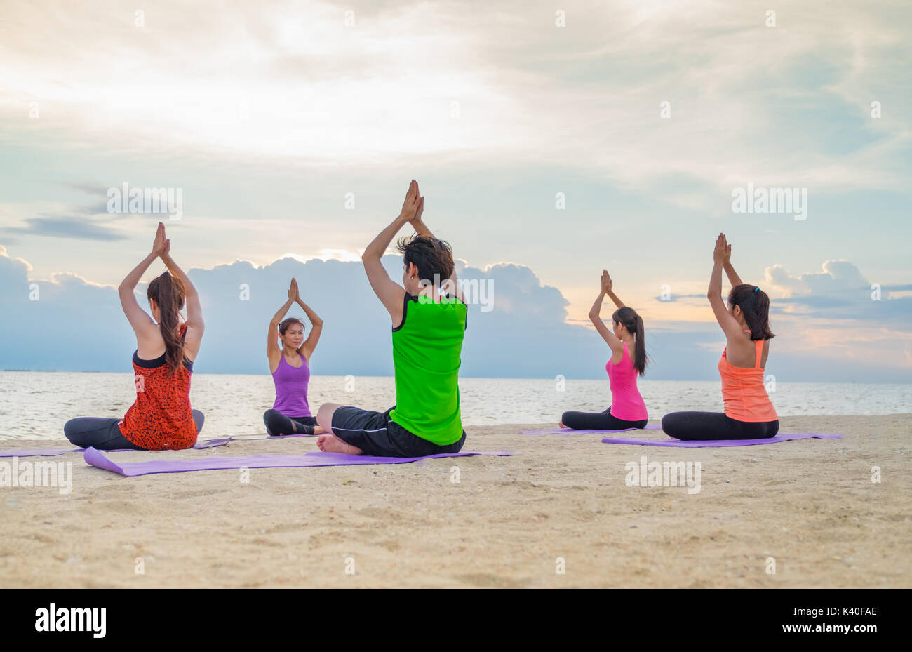 Classe di yoga in mare spiaggia di tramonto ,Gruppo di persone facendo namaste pone con vongole emozione relax in spiaggia,Meditazione pongono,di benessere e salute b Foto Stock