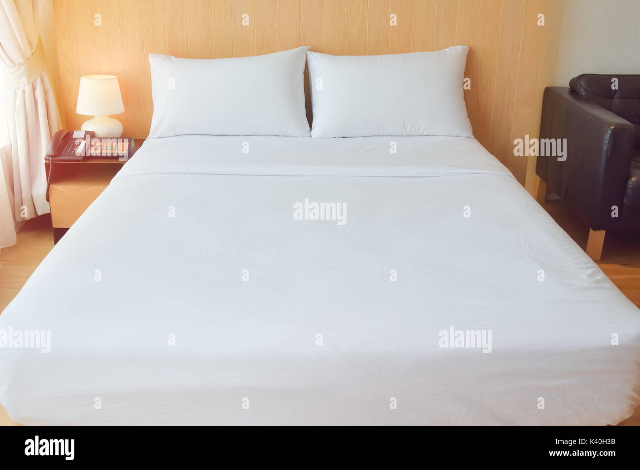 Confortevole letto bianco in camera per un arredamento confortevole e vestiti di fornire. Foto Stock