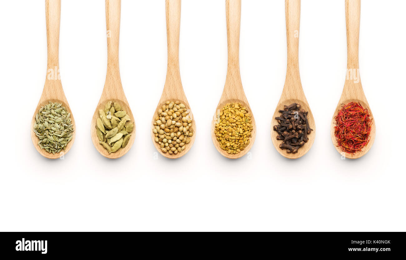 Cucchiaio di legno riempita con varie spezie su sfondo bianco Foto Stock