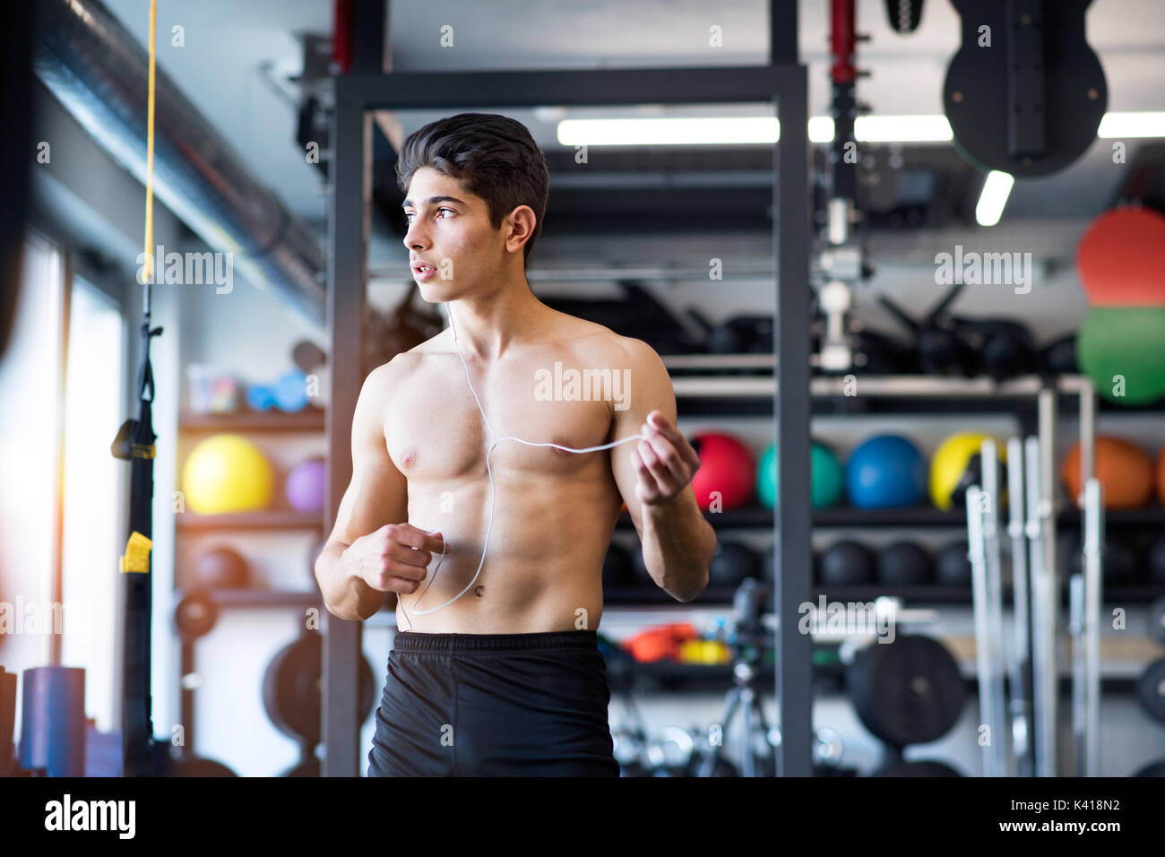 Uomo ispanico in palestra in appoggio, tenendo gli auricolari, ascolto di  musica Foto stock - Alamy