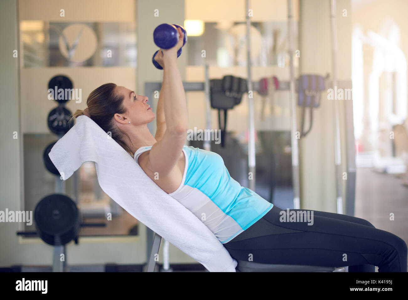Attraente donna di mezza età che lavora fuori in una palestra di formazione con una coppia di manubri in una vista ravvicinata in una salute e concetto di fitness Foto Stock