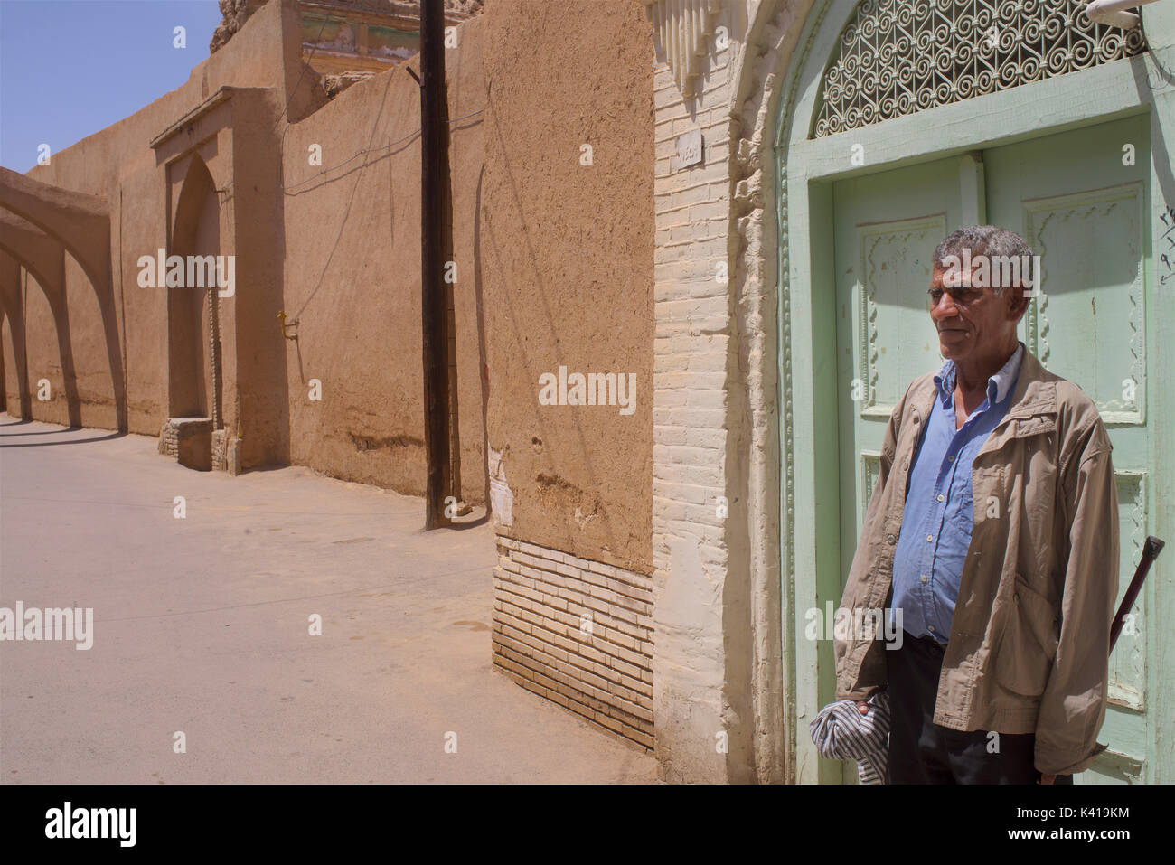 Uomo iraniano si ferma per una sessione di conversazione testuale nelle vecchie strade di Yazd, Iran Foto Stock