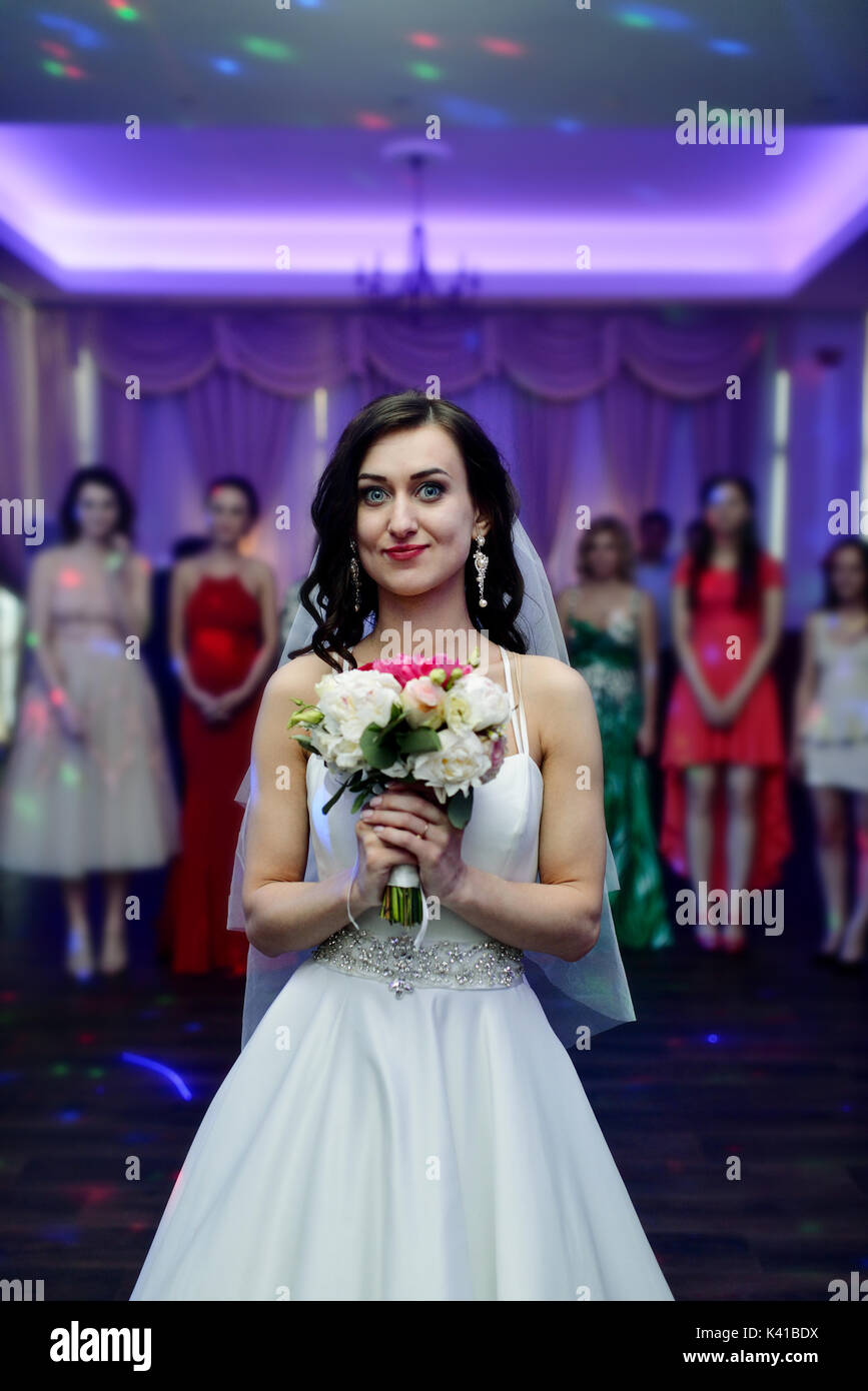 Bellezza sposa in abito nuziale con velo di pizzo sta gettando Bouquet nozze in ambienti interni Foto Stock