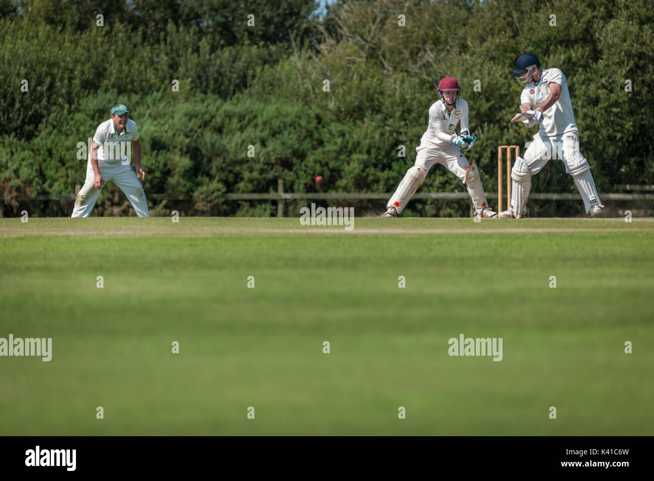 Un battitore gioca un colpo durante una domenica League match tra due locali squadre di cricket. Foto Stock