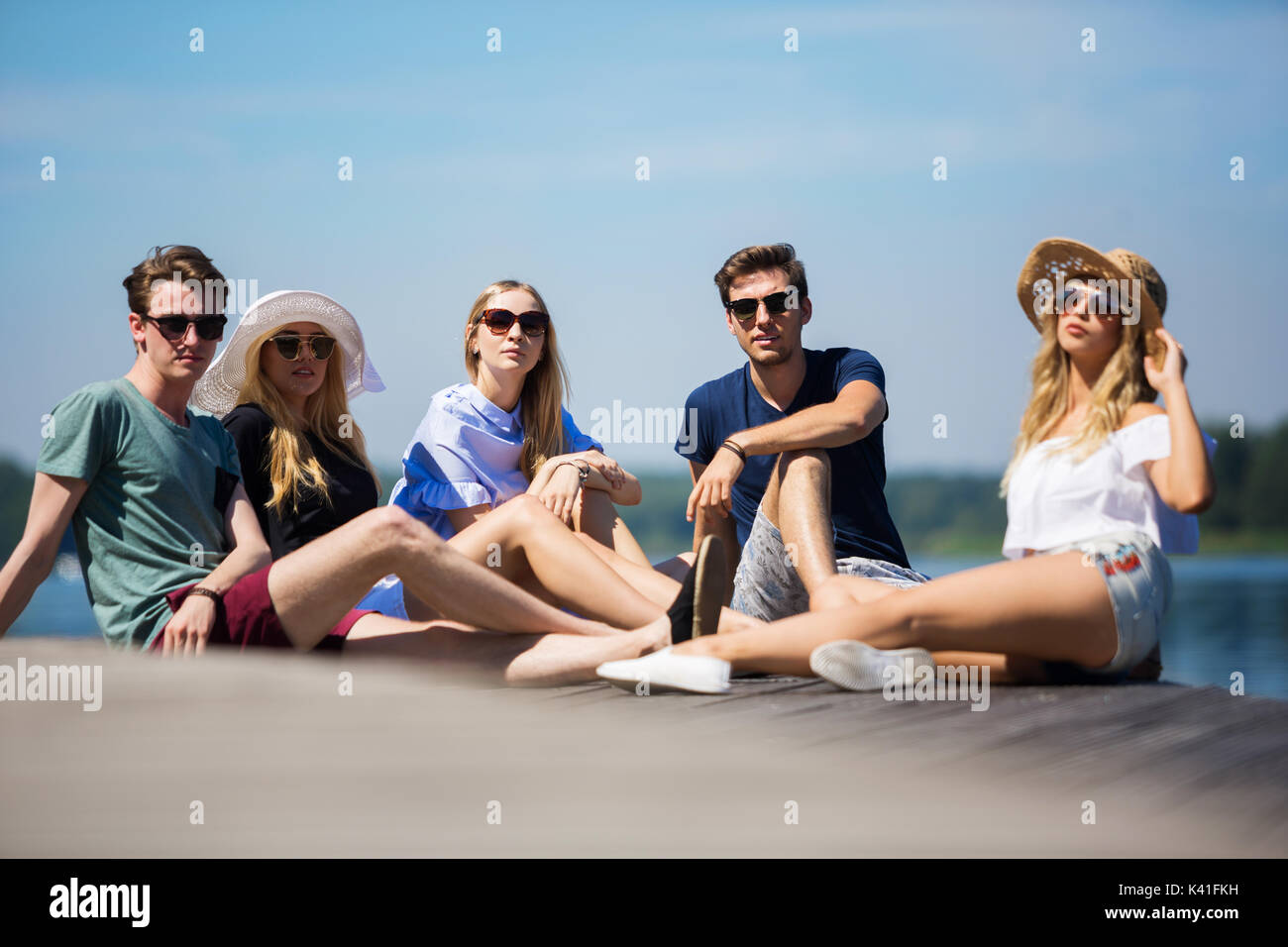 Una foto di gruppo di amici seduti sul molo e rilassante. Foto Stock