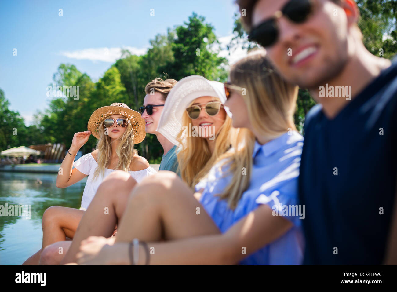 Una foto di gruppo di amici seduti al lago e rilassante. Foto Stock
