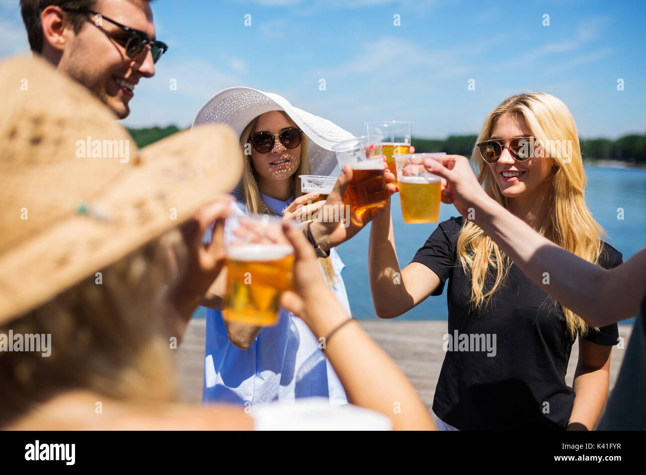 Una foto di gruppo di amici partying al lago e bere birra. Foto Stock
