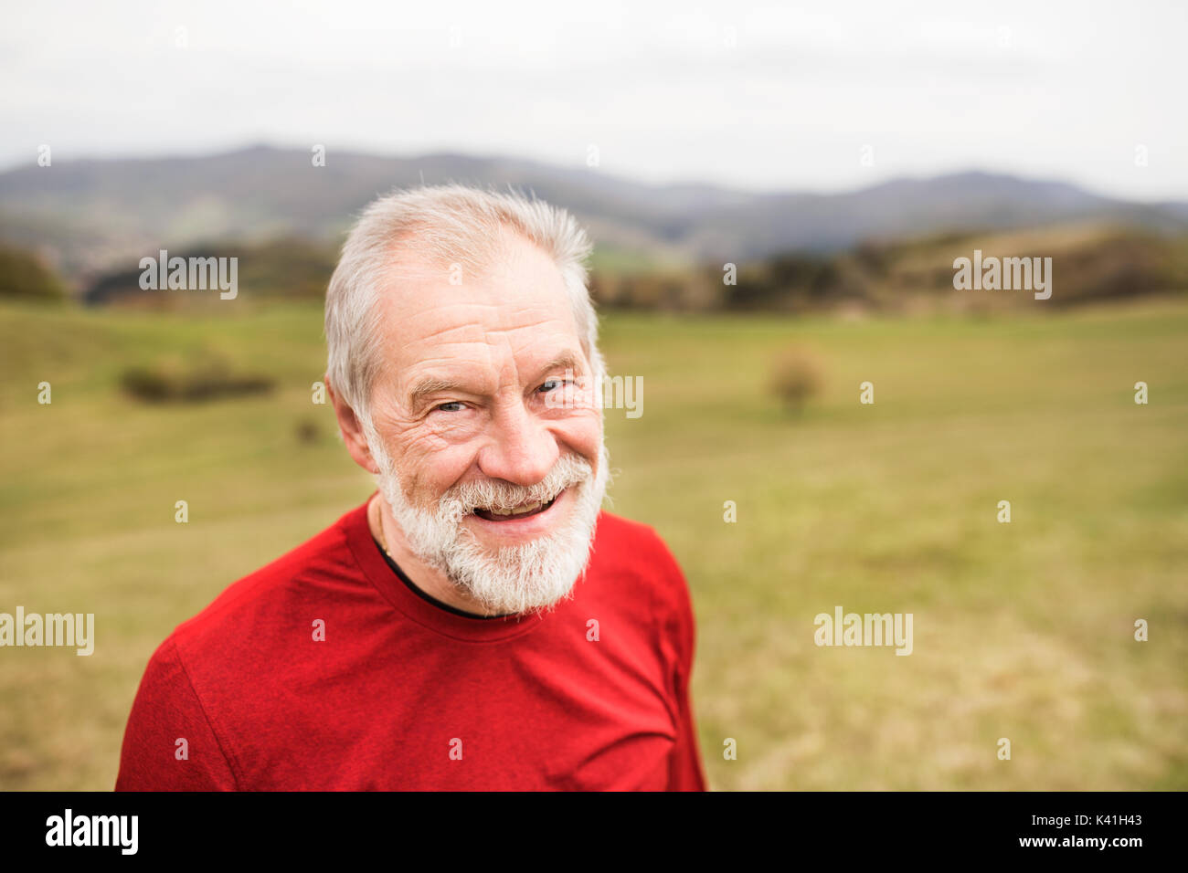 Active senior runner in felpa rossa in natura in appoggio. Foto Stock