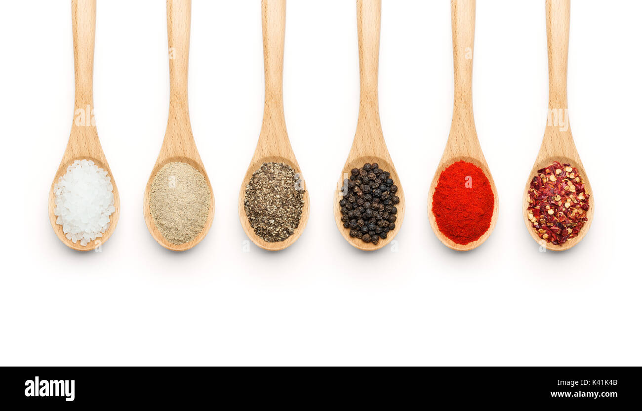 Cucchiaio di legno riempita con varie spezie su sfondo bianco Foto Stock