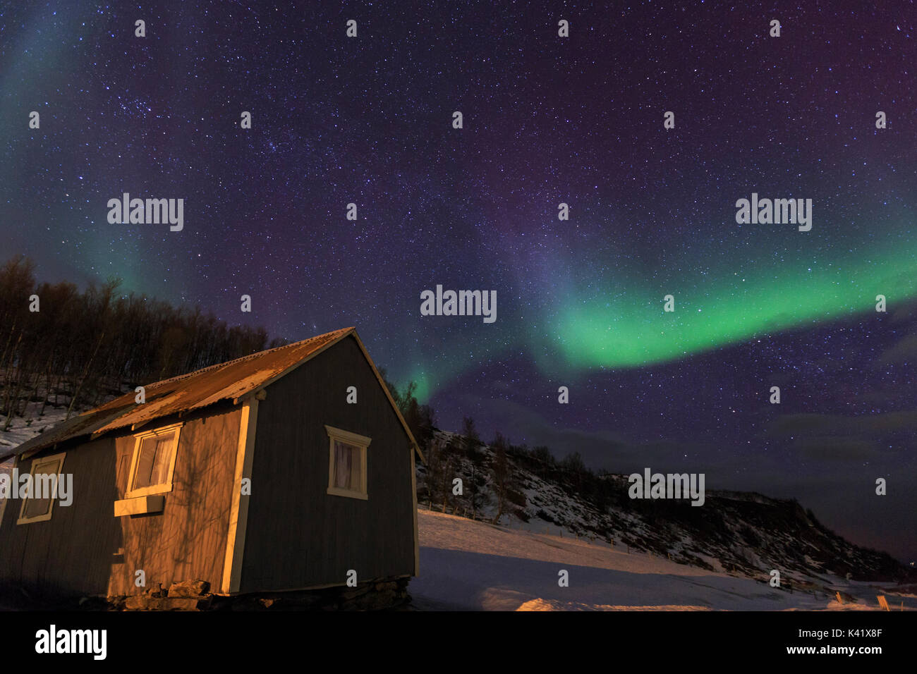Northern Lights illumina la cabina in legno a Svensby Alpi Lyngen Tromsø Lapponia Norvegia Europa Foto Stock