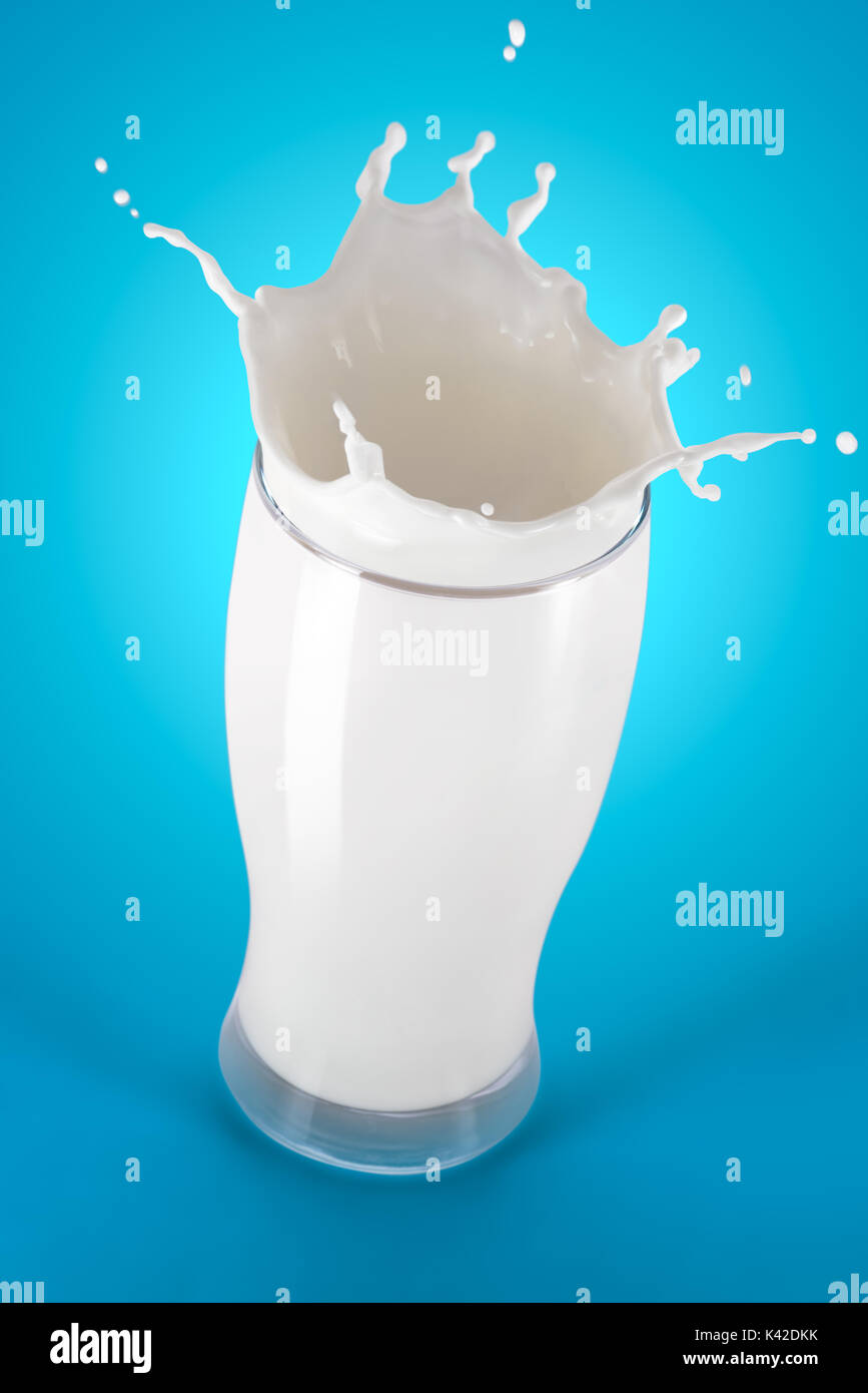 Latte fresco splash in un bicchiere su sfondo blu Foto Stock