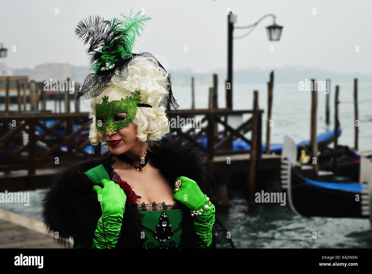 Una donna in un bel verde costume durante il Carnevale di Venezia con le gondole in background. Foto Stock