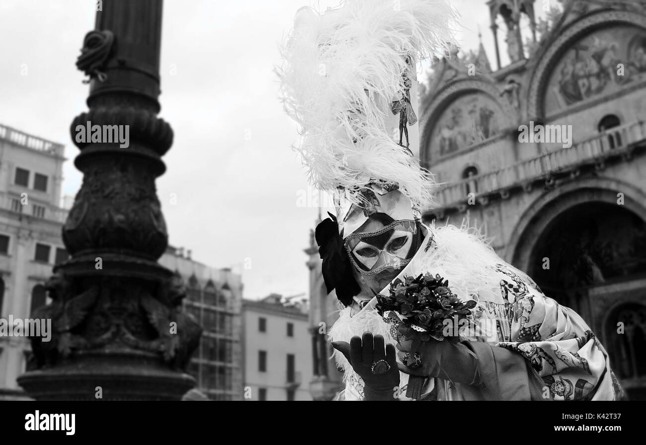 Una persona in costume in una mascherata durante il Carnevale di Venezia, con le piume di grandi dimensioni sulla parte superiore del suo cappello. Foto Stock