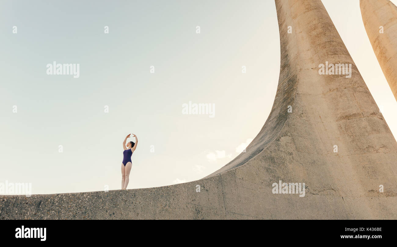 Ballet artista pratica di danza si sposta all'esterno. Ballerino femmina in piedi su un monumento la pratica di passi di danza. Foto Stock