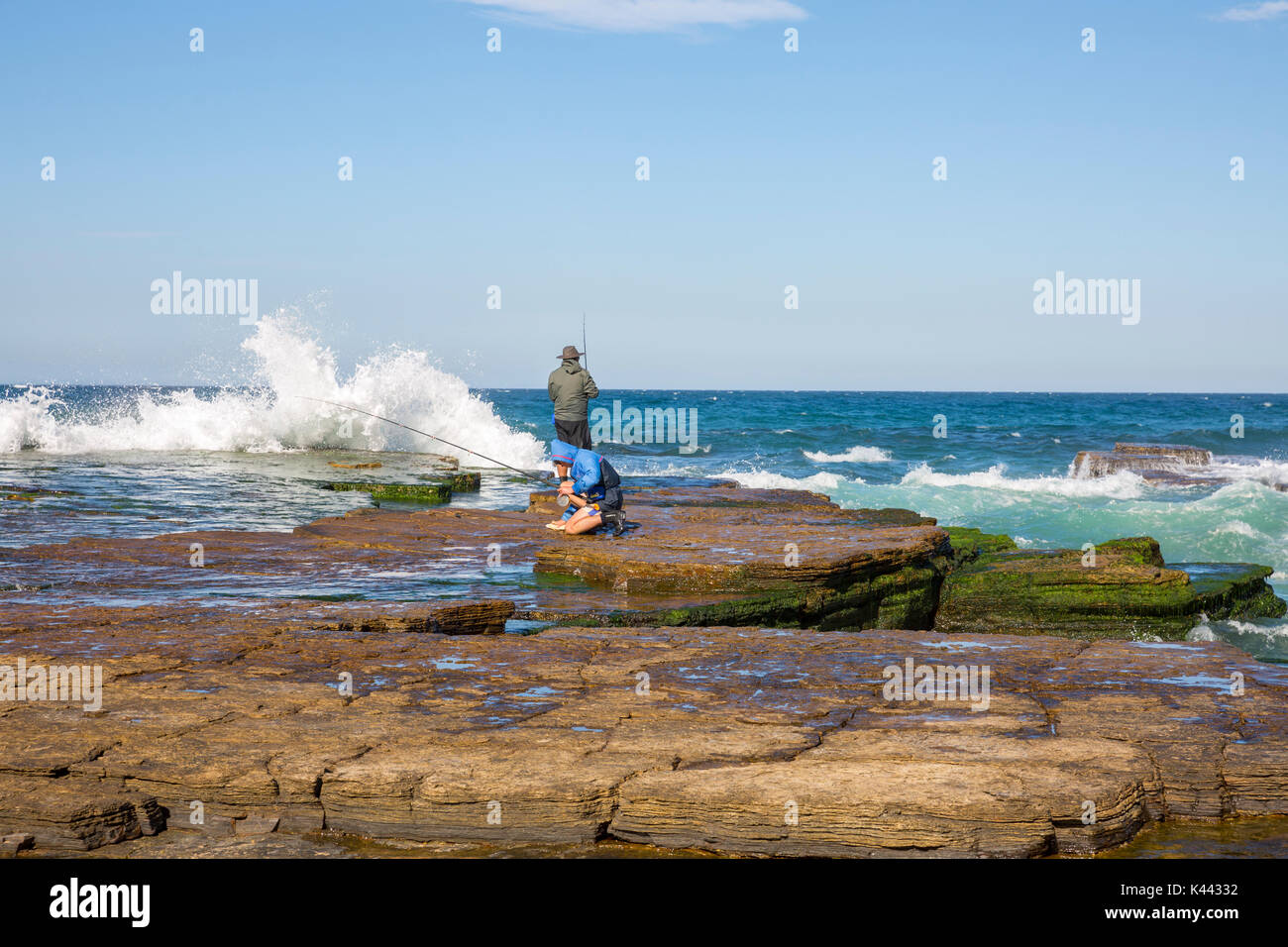 Due uomini australiani rock pesca al largo della costa a Turimetta beach Sydney , Australia Foto Stock