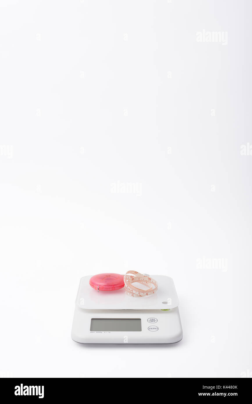 Alimento bianco bilance con tapeline rosa per misurare le dimensioni del corpo, su sfondo bianco Foto Stock
