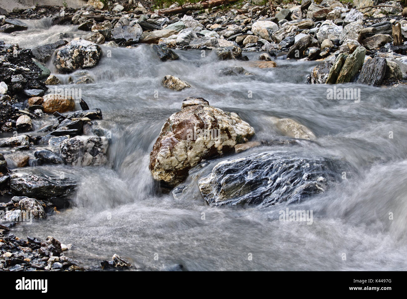 Massi in un piccolo ruscello di montagna circondato da una fluidità acqua (tempo di esposizione lungo) Foto Stock