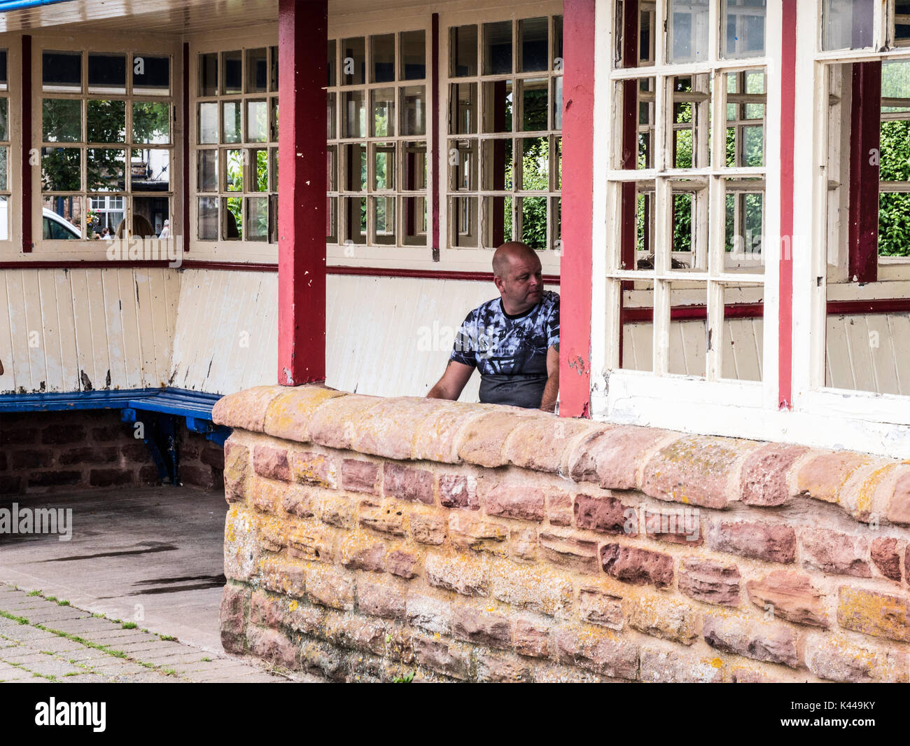 Un uomo seduto in un rifugio sul lungomare a Minehead nel Somerset. Foto Stock