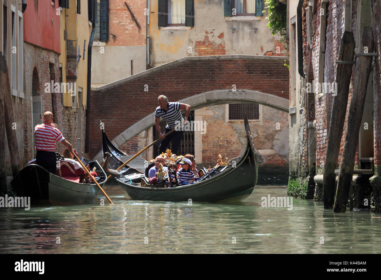 Gondolieri si incontrano in prossimità di un ponte su un canale di Venezia, Italia Foto Stock