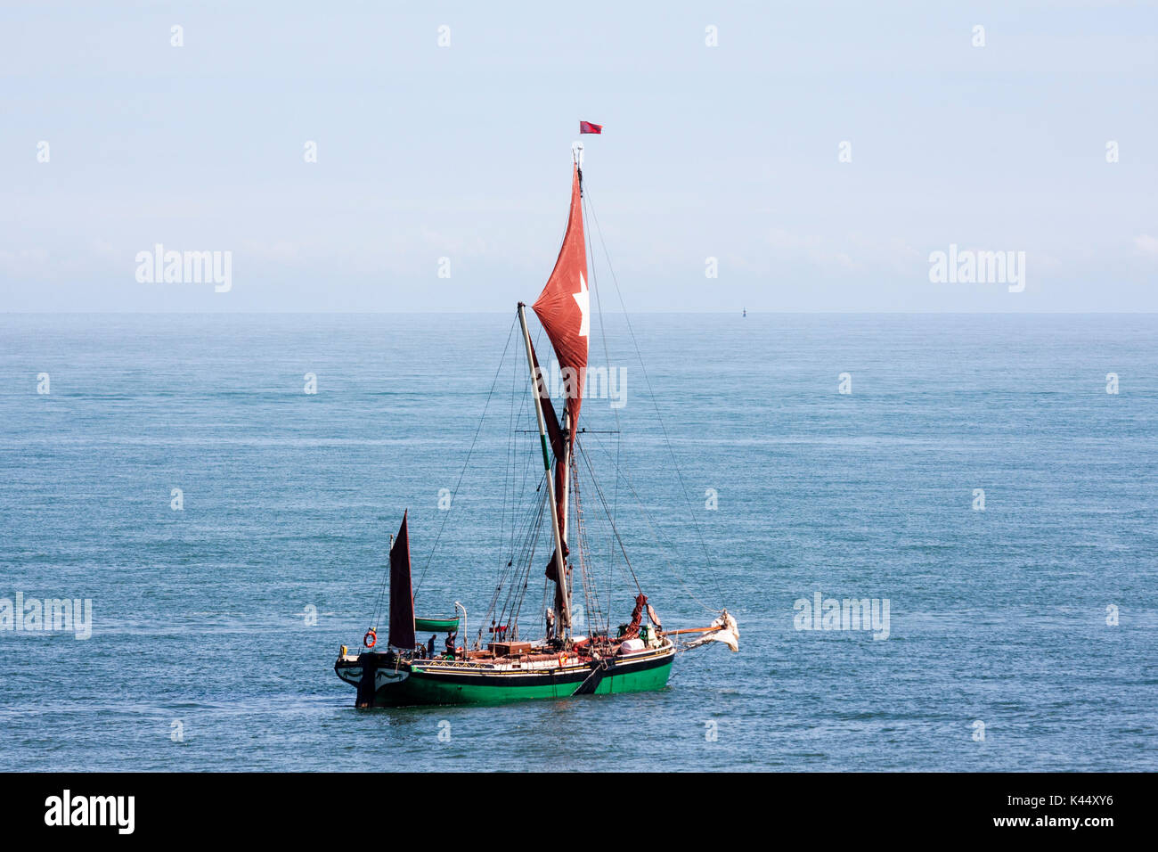 Inghilterra, Broadstairs. Il Tamigi Barge vela in mare. Distante shot. Montante singolo battello sullo sfondo del mare e cielo nebuloso. Foto Stock