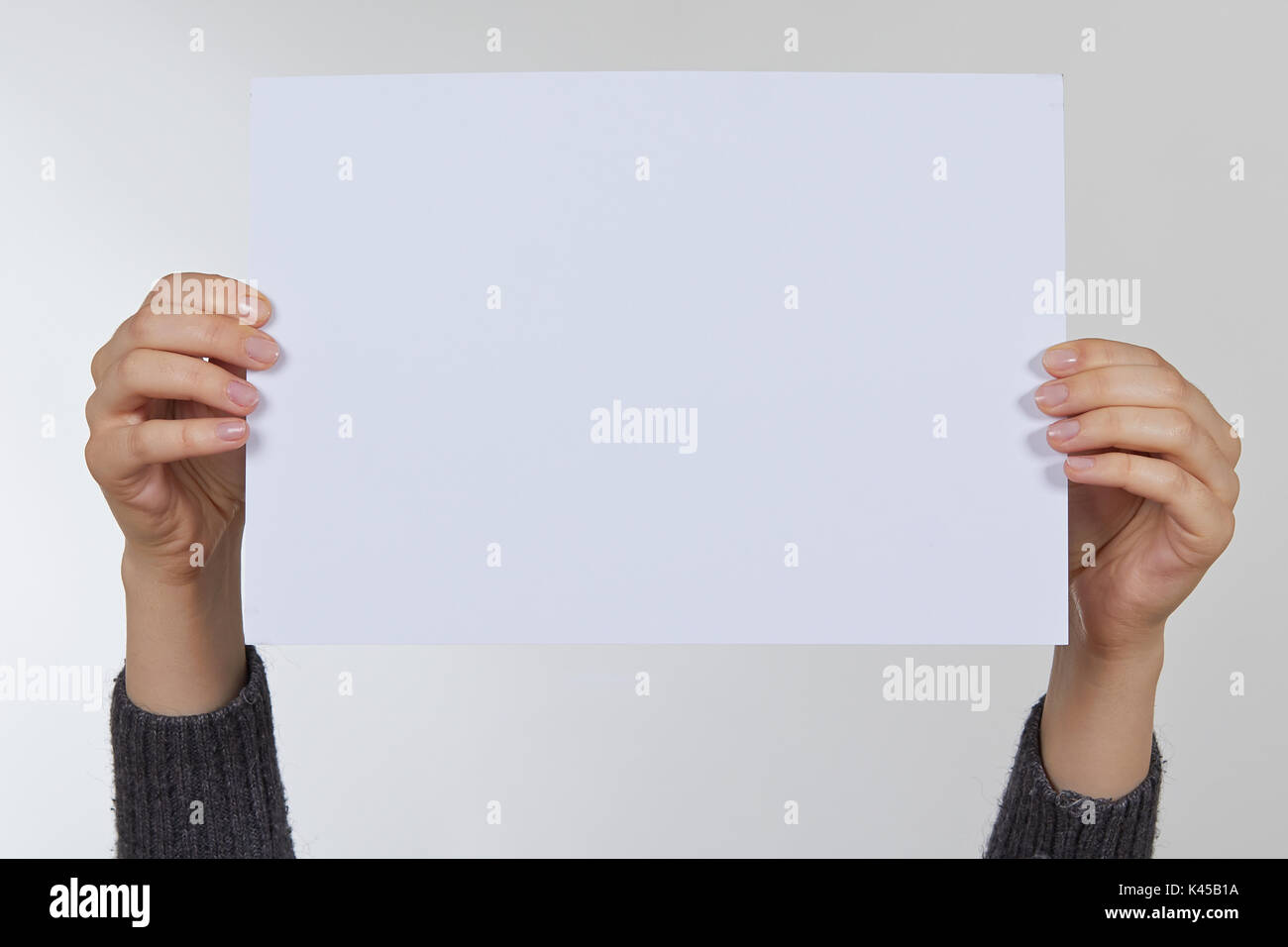 Mano che tiene la carta isolato su bianco Foto Stock