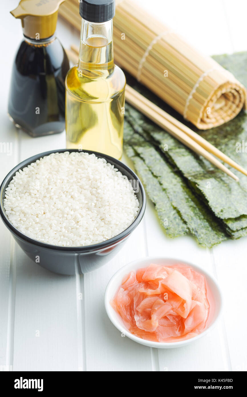 Il sushi ingredienti sul tavolo bianco. Riso, lo zenzero, la salsa di soia, aceto e nori fogli. Foto Stock